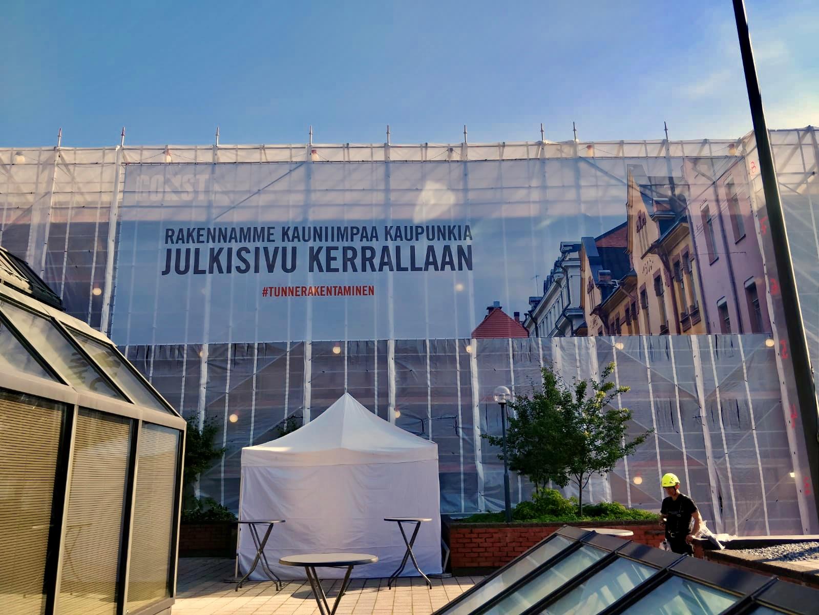 Telinepeitteeseen painettu teksti Rakennamme kauniimpaa kaupunkia julkisivu kerrallaan, edessä kattoterassi
